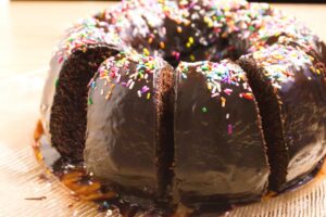chocolate buttermilk bundt cake shown slices with sprinkles on chocolate frosting